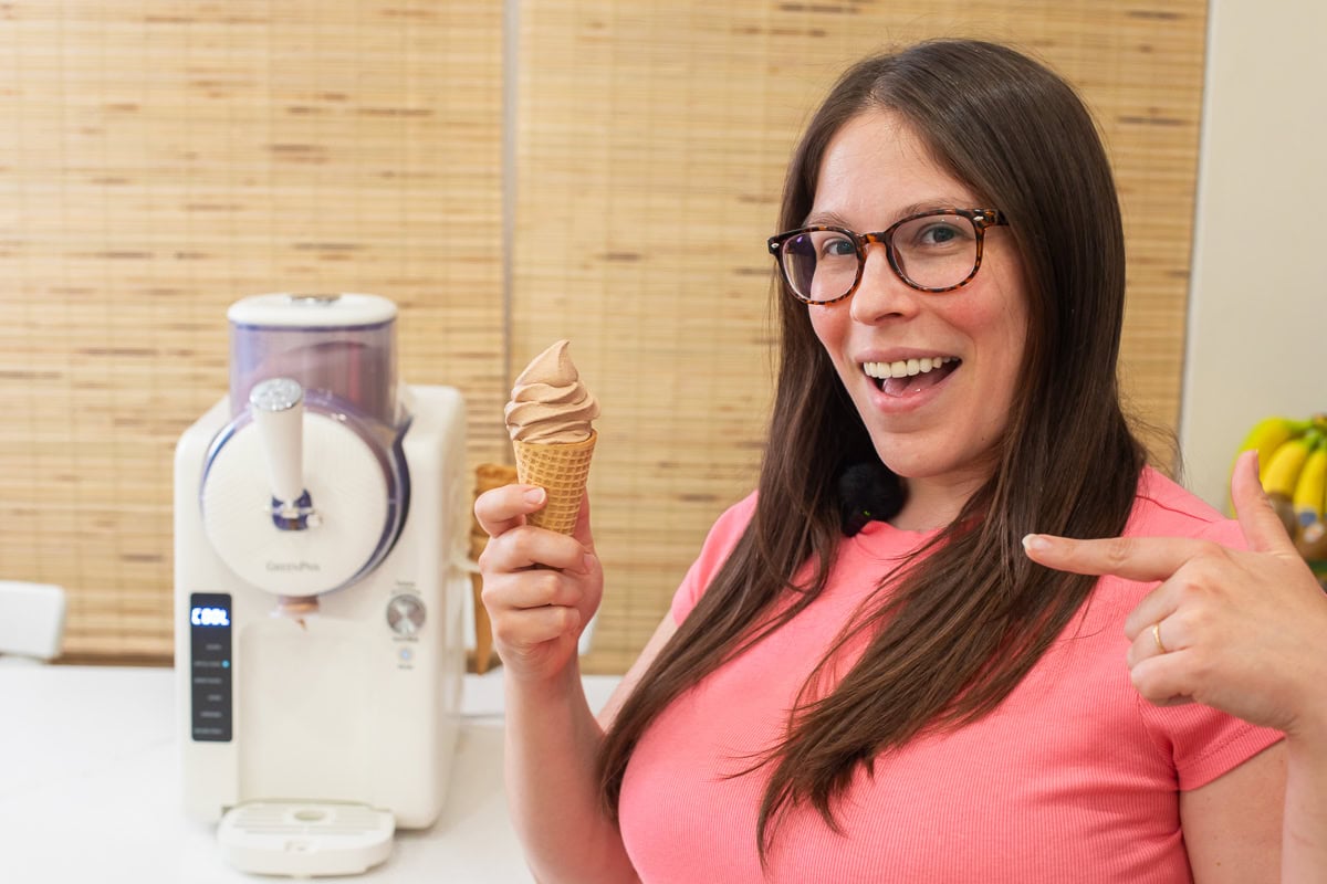Happy woman holding a homemade chocolate soft serve cone made with the GreenPan Frost machine.