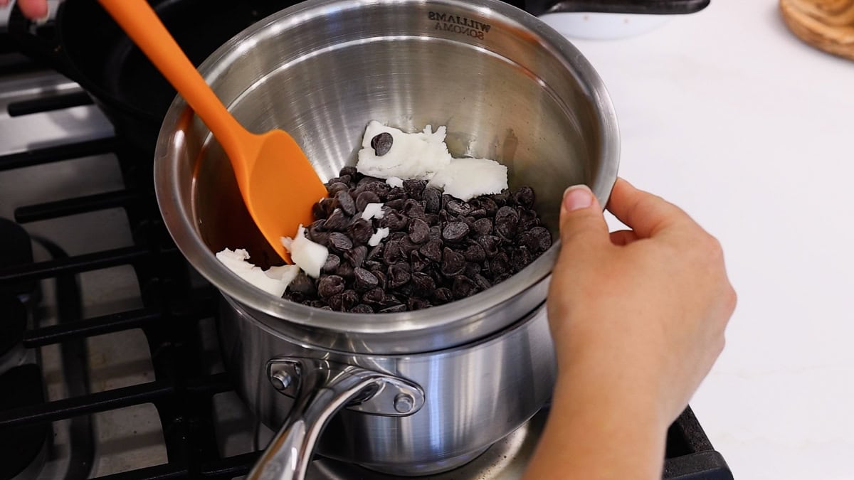 Chocolate chips and solid coconut oil in the top pot of a double boiler, ready to be melted.