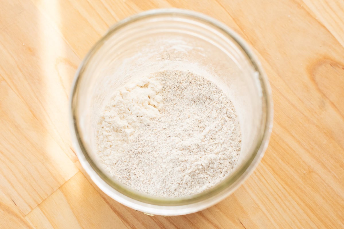 Top view of dry rye and all-purpose flour mixture in a glass jar for starting sourdough.