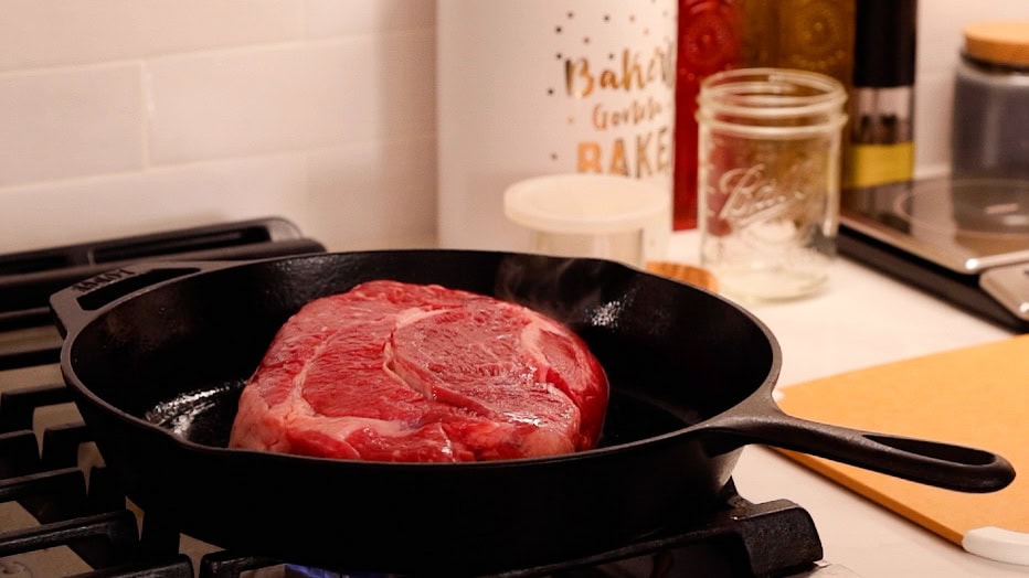 Uncooked chuck roast placed searing in a hot cast iron skillet.
