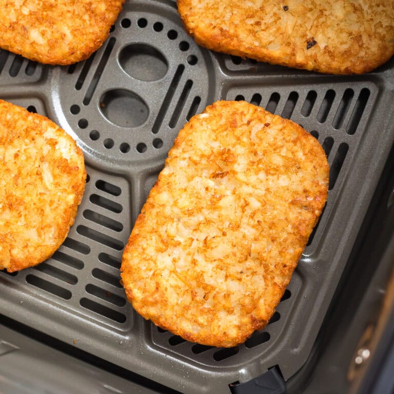 close up photo of air fryer frozen hash browns in air fryer basket.