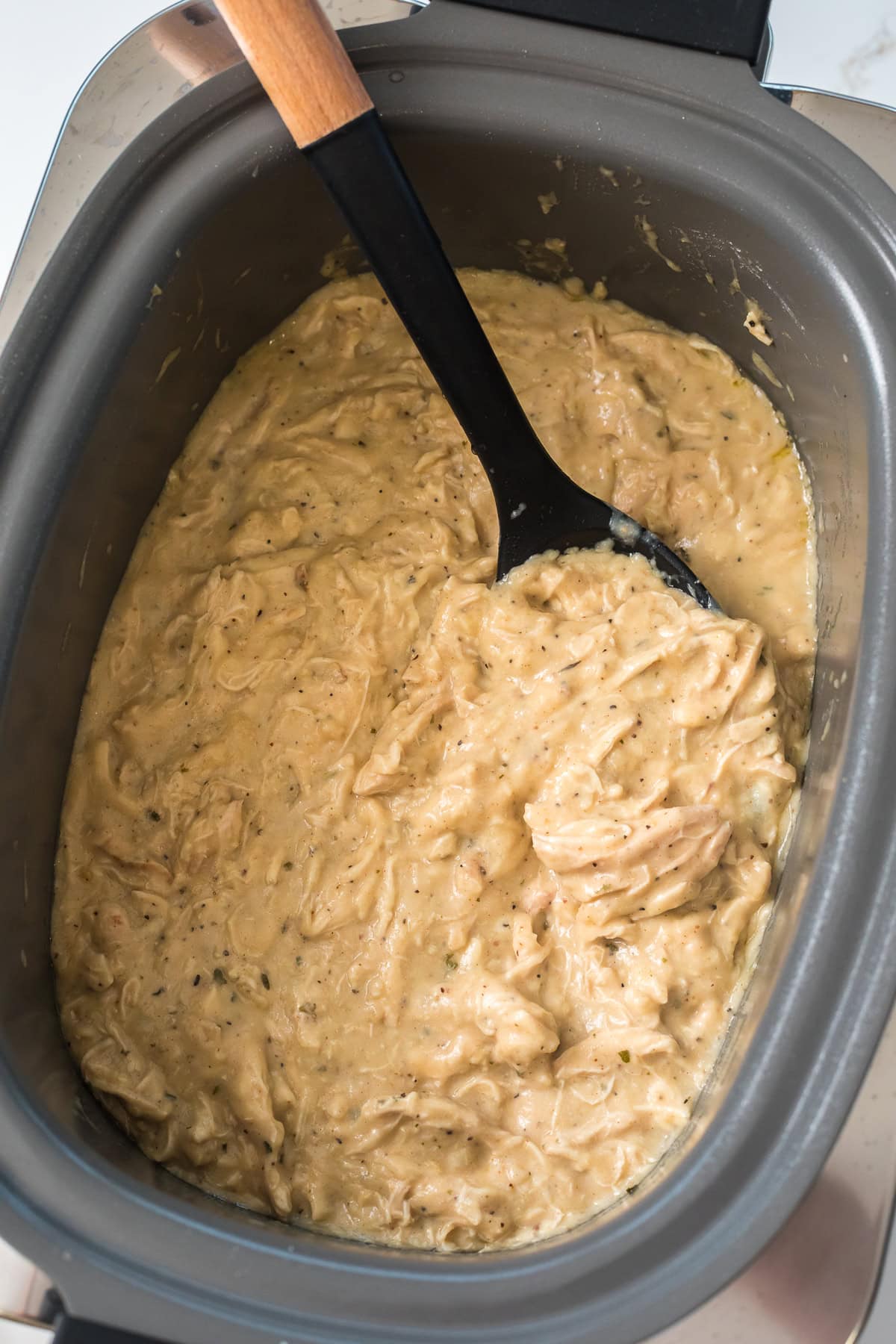 Shredded chicken coated in thick, creamy gravy inside the slow cooker, ready to serve.