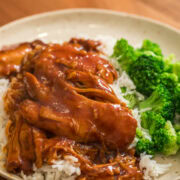 Slow cooker honey garlic BBQ chicken served over white rice with steamed broccoli on a plate.