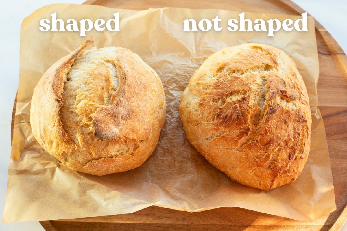 Two round loaves of golden no-knead bread resting on parchment paper on a wooden board with text above them saying shaped and no shaped.