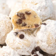 Chocolate chip snowball cookies arranged on a plate with a cut cookie revealing chocolate chips inside.