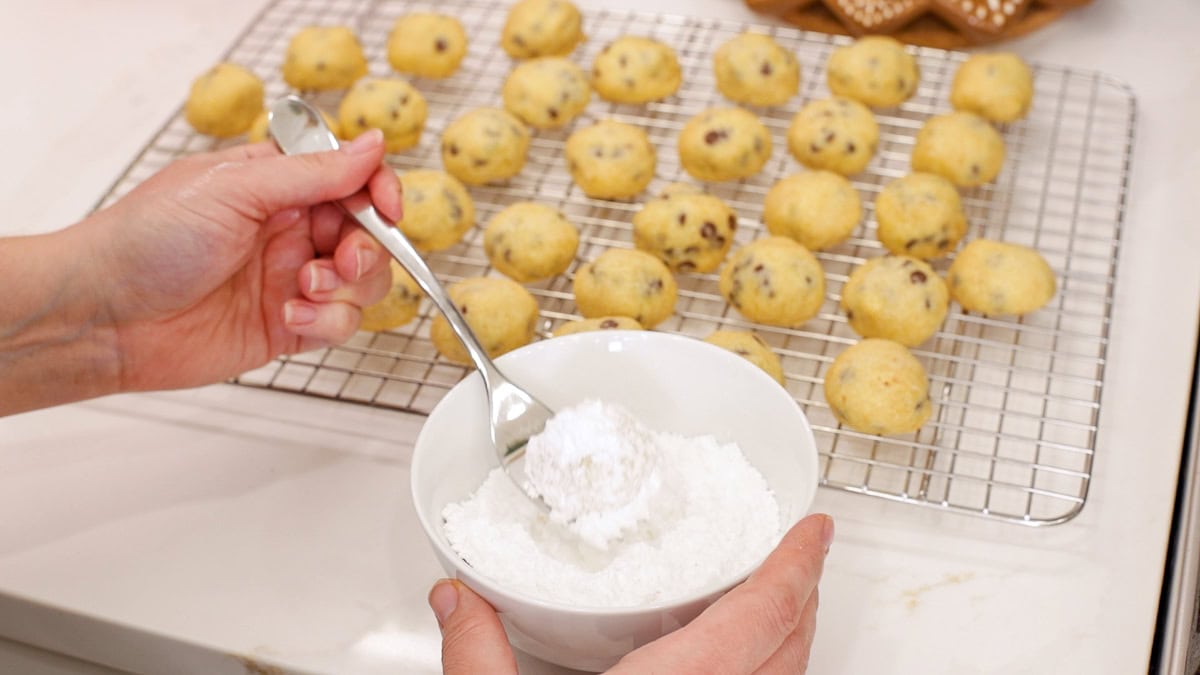 Covering chocolate chip snowball cookies in powdered sugar.
