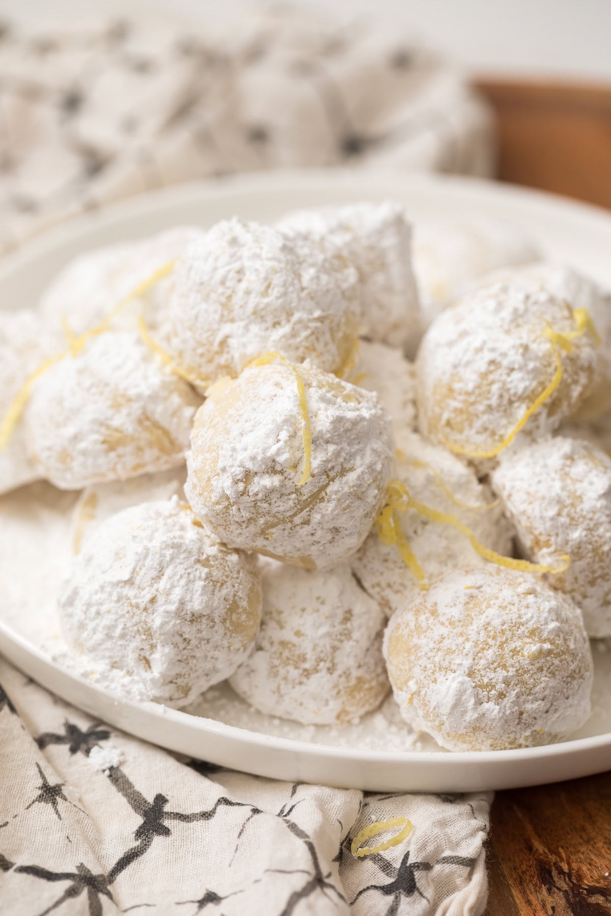 Lemon snowball cookies coated in powdered sugar on a plate.