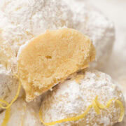 Close-up of powdered sugar covered lemon snowball cookies with one cut in half.