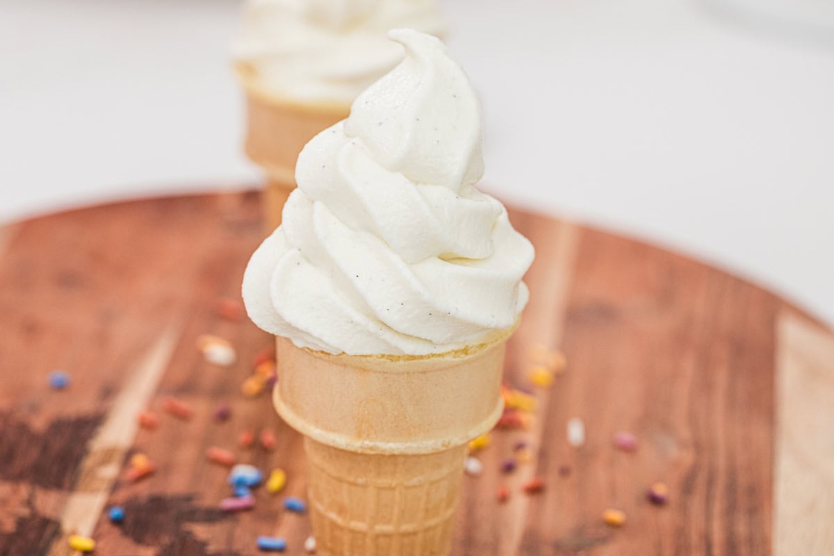 Vanilla soft serve ice cream cones served on a wooden board.