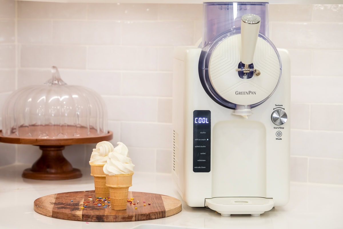 GreenPan Frost frozen ice cream and frozen drink maker next to freshly made vanilla soft serve cones.