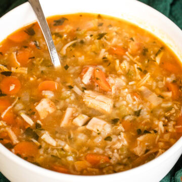 close up of rotisserie chicken and rice soup in a white bowl.