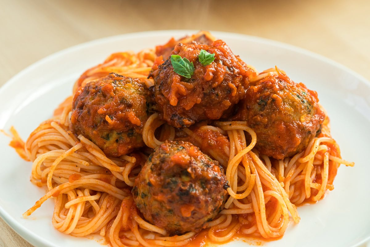baked chicken meatballs on a plate with spaghetti and sauce.
