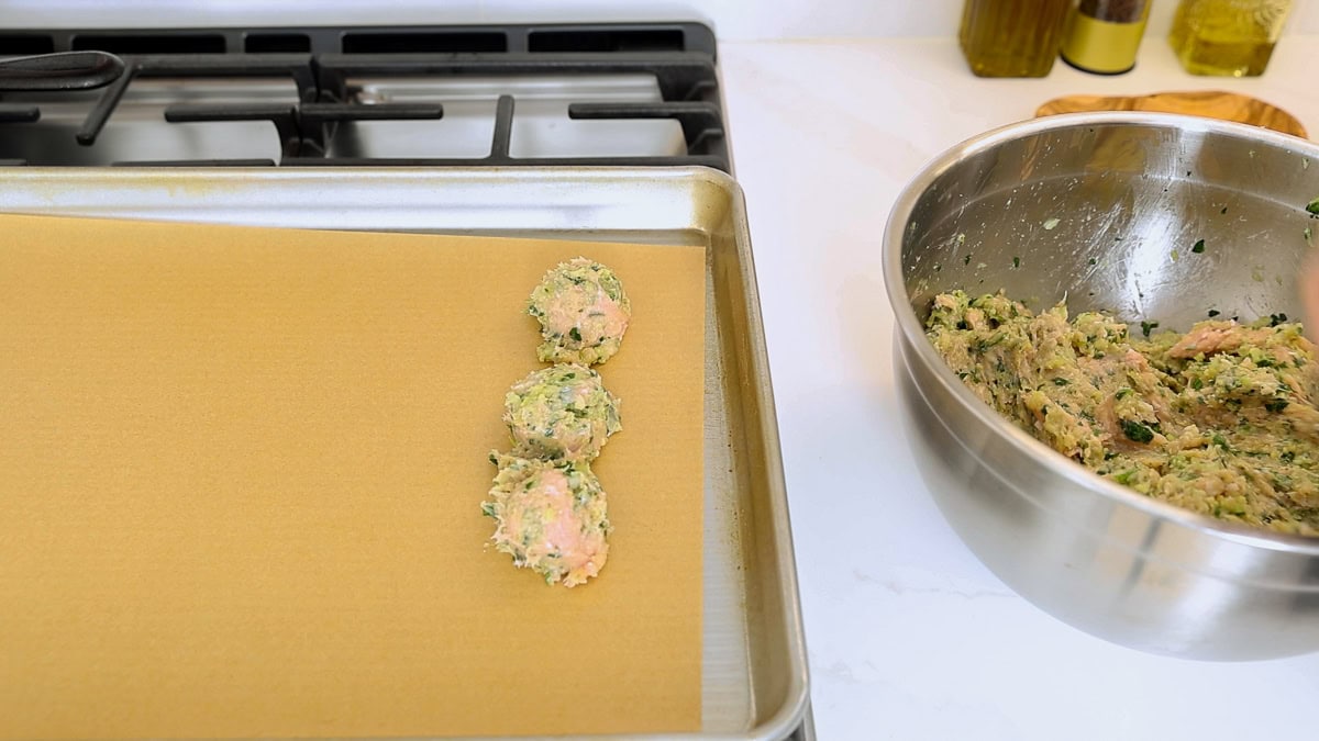raw baked chicken meatballs on a baking sheet.