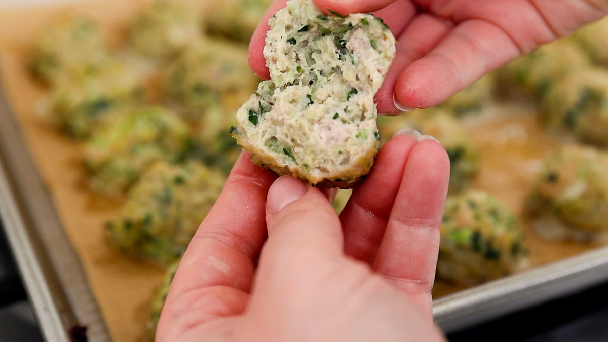 hands showing inside of chicken meatball.