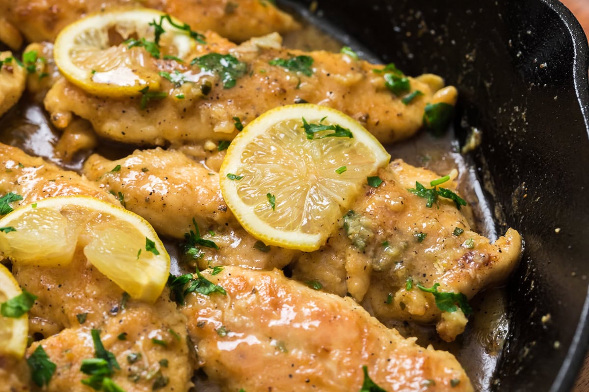 Tender chicken tenderloins in a bright lemon garlic sauce served in a cast iron skillet garnished with lemon slices and parsley.