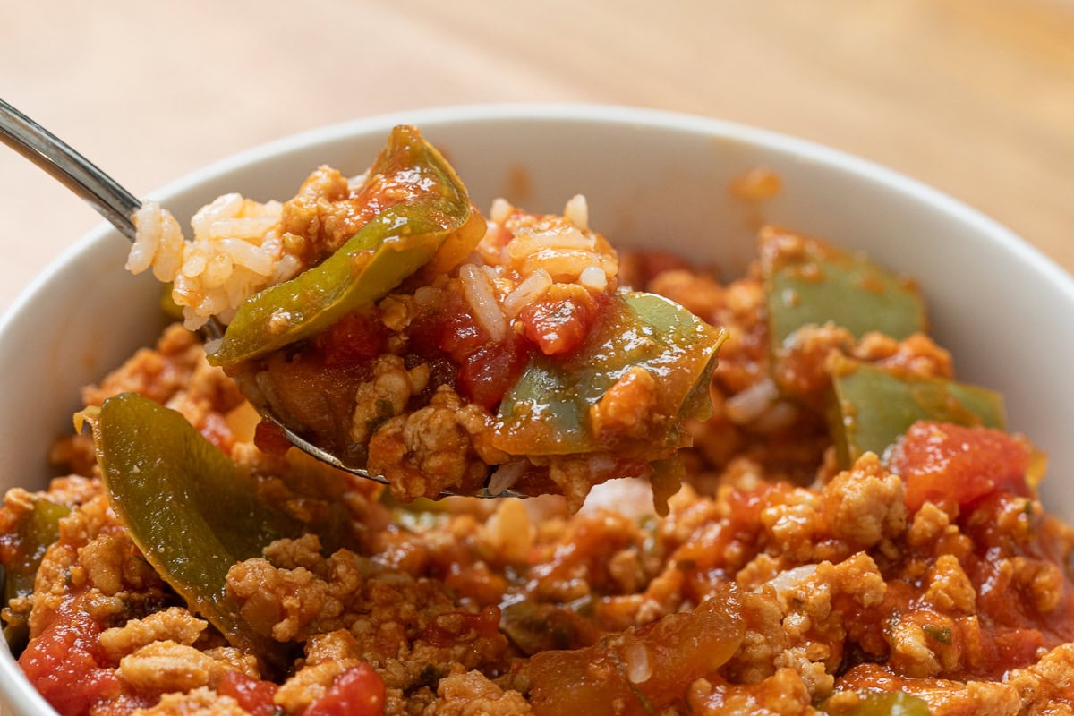 Close up of a spoonful of ground chicken unstuffed peppers with rice, peppers, and tomato sauce.