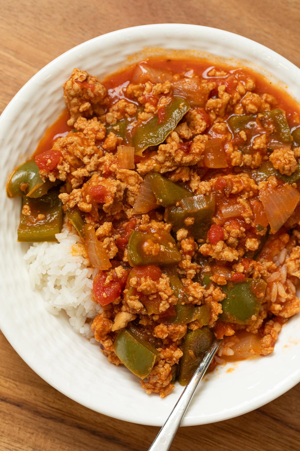 Ground chicken unstuffed pepper skillet with chopped green peppers, onions, and tomatoes served over rice.