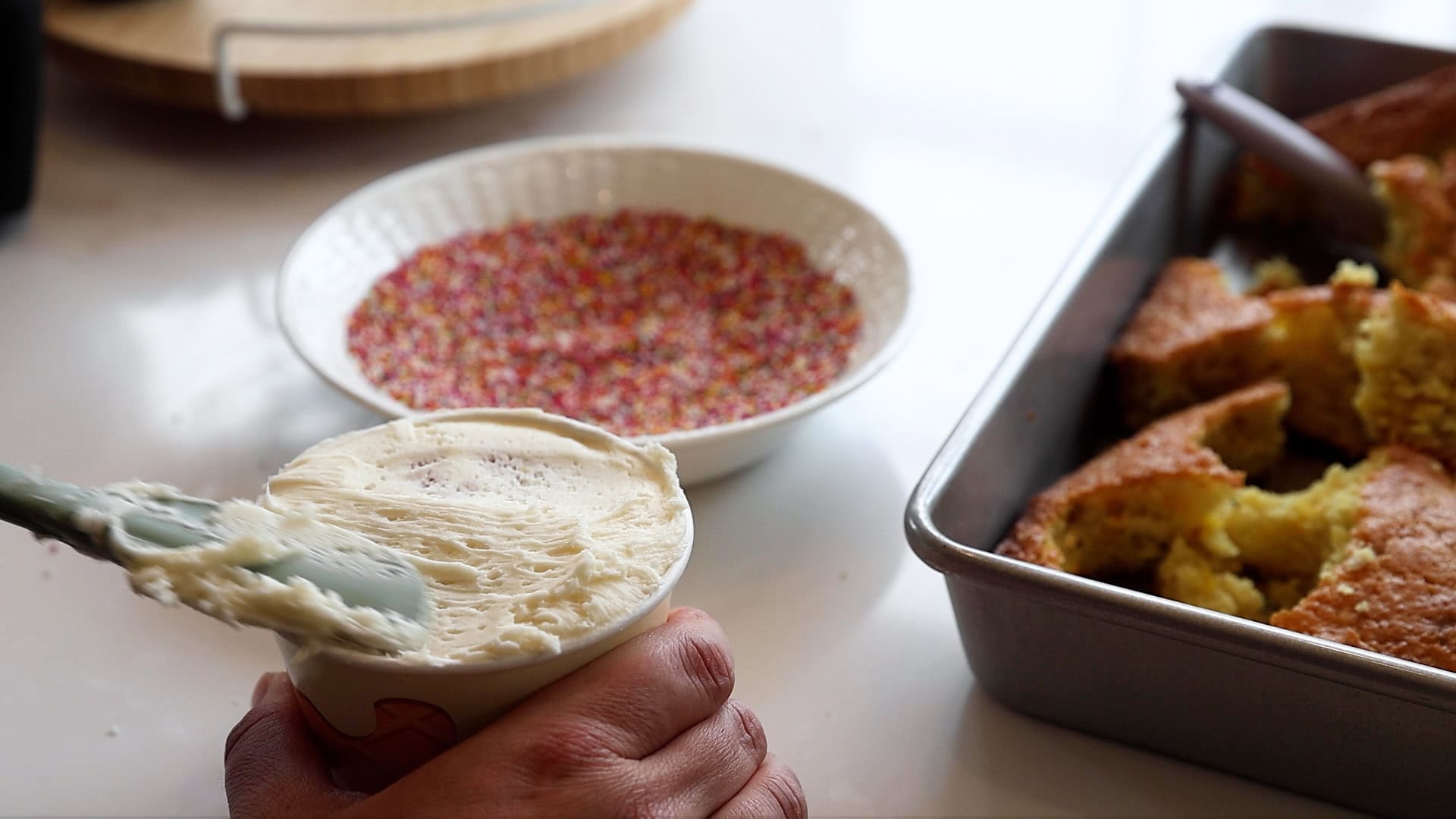 spreading buttercream on mini cake in snack cup for dot cakes.