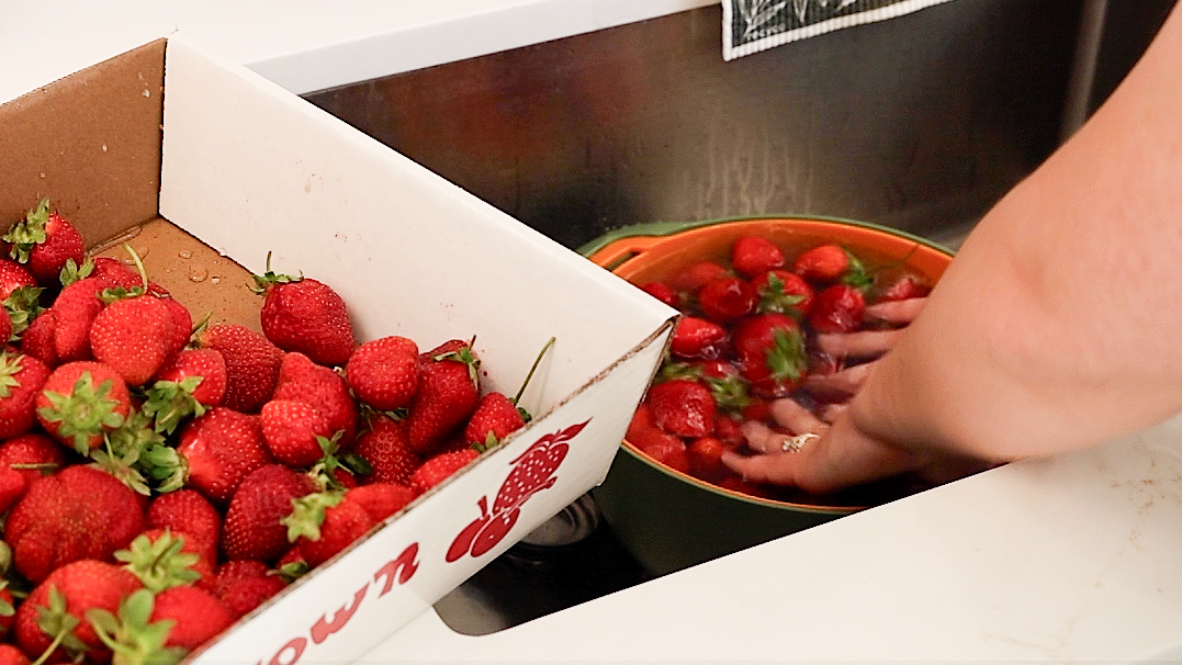hands washing strawberries in colander