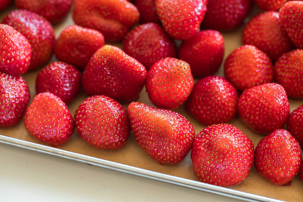 strawberries on parchment lined baking sheet for freezing.