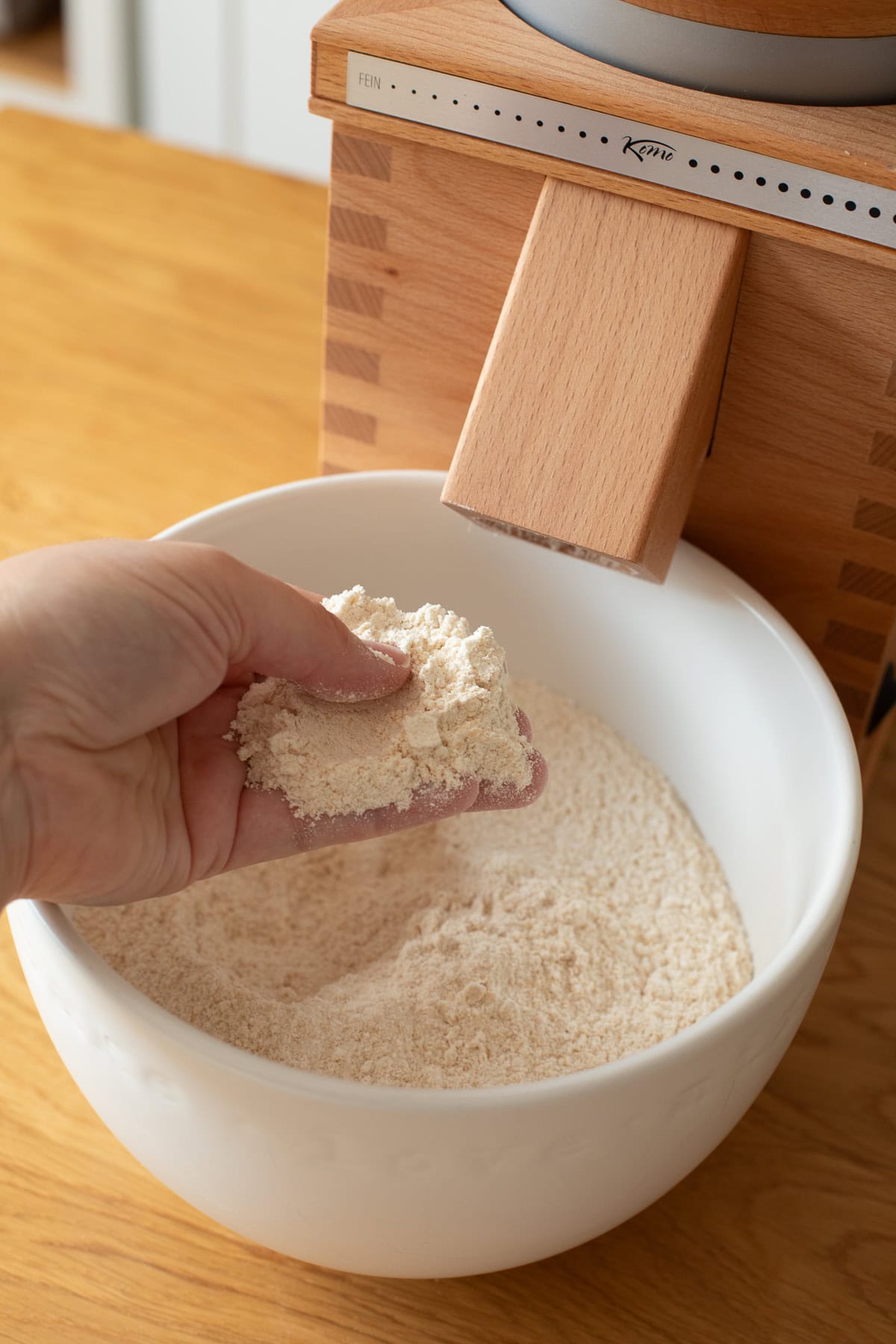 hand feeling fresh milled flour in a bowl.