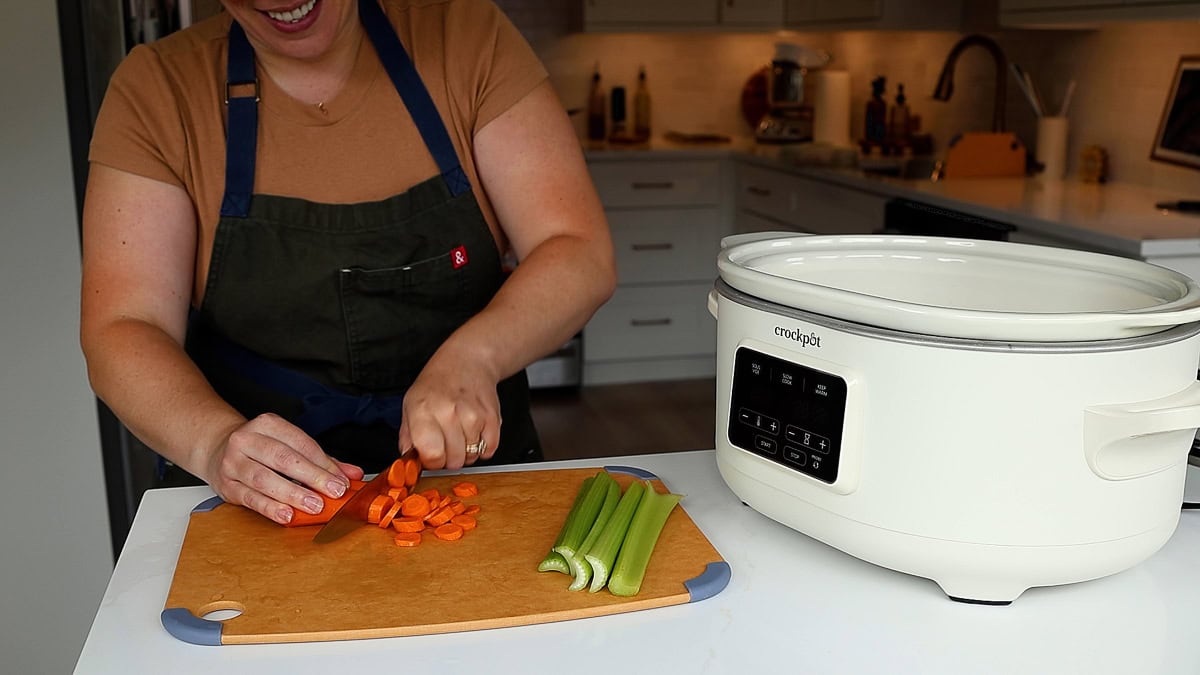 woman smiling slicing carrots.