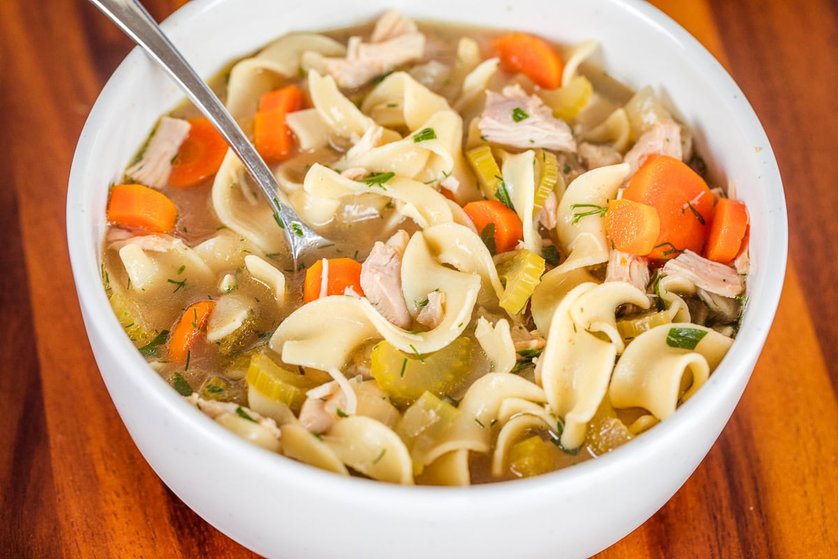 Bowl of slow cooker chicken noodle soup with a spoon.