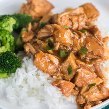 homemade slow cooker teriyaki chicken over rice with broccoli on a white plate.