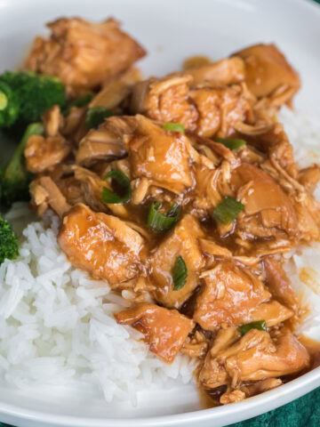 Slow cooker chicken teriyaki over rice with broccoli on a white plate.