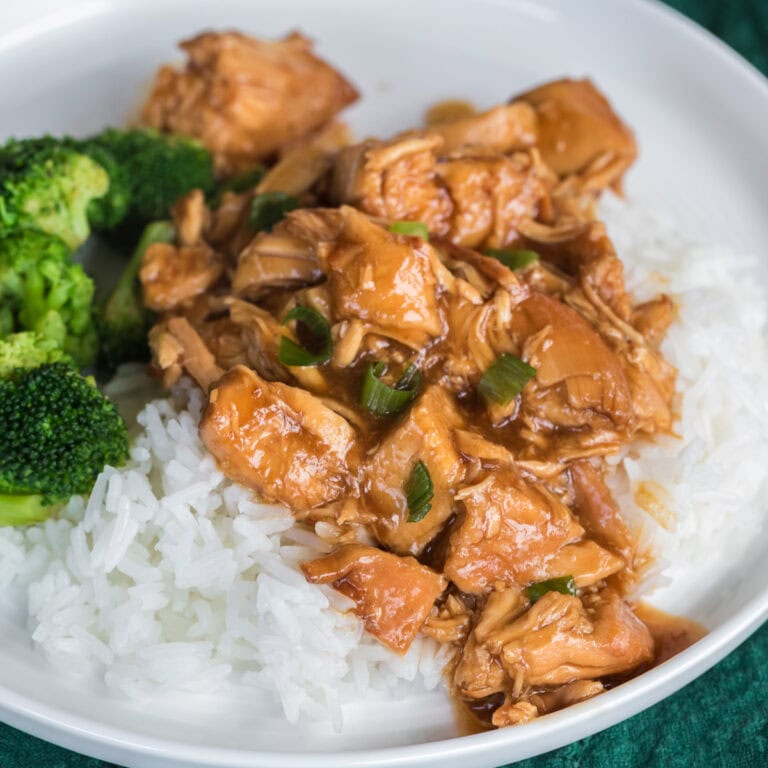 Slow cooker chicken teriyaki over rice with broccoli on a white plate.