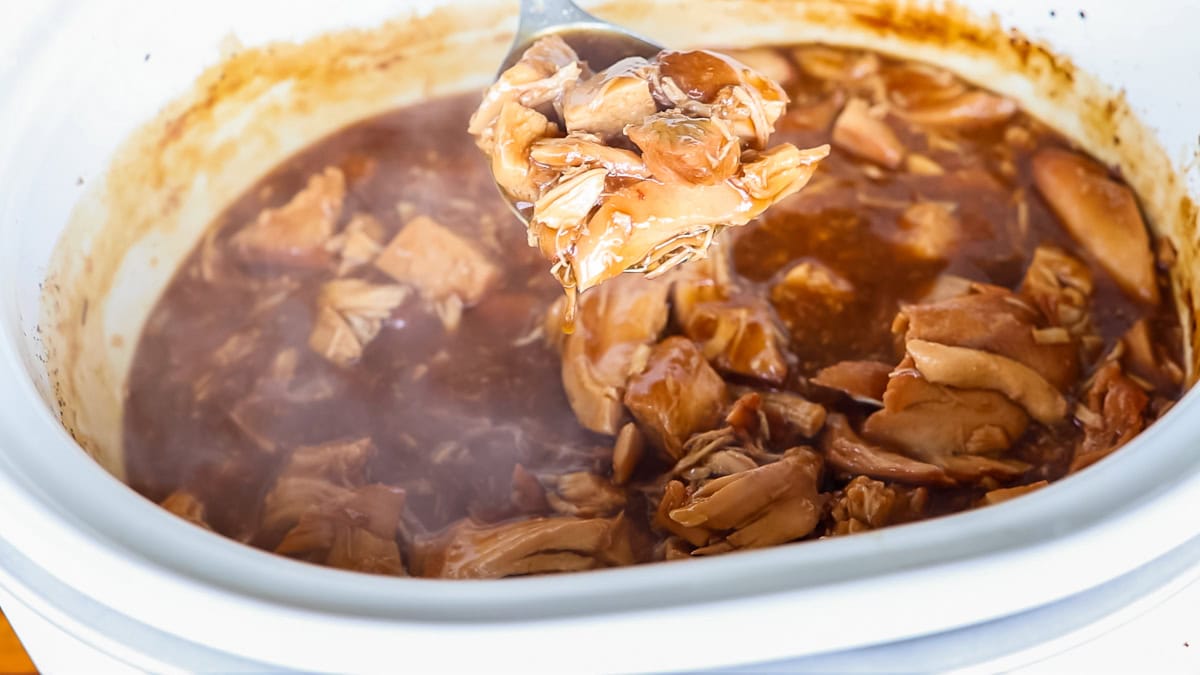 steaming teriyaki chicken in slow cooker on a serving spoon.