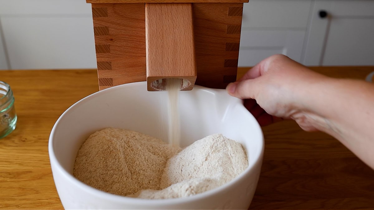 komo mill milling wheat berries into fresh milled flour in a white bowl.