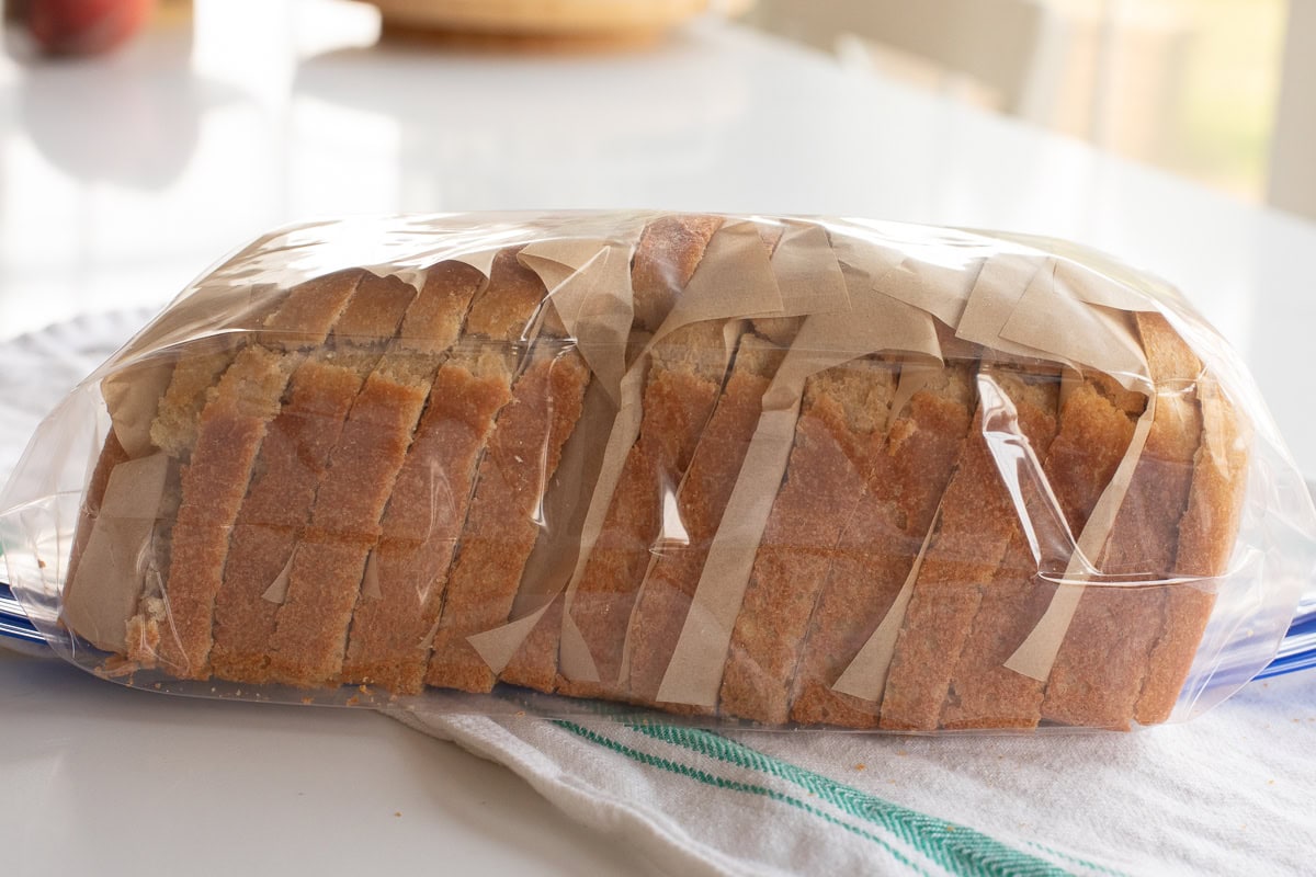 picture showing how to freeze bread by using parchment paper pieces in between each slice in a freezer safe bag.