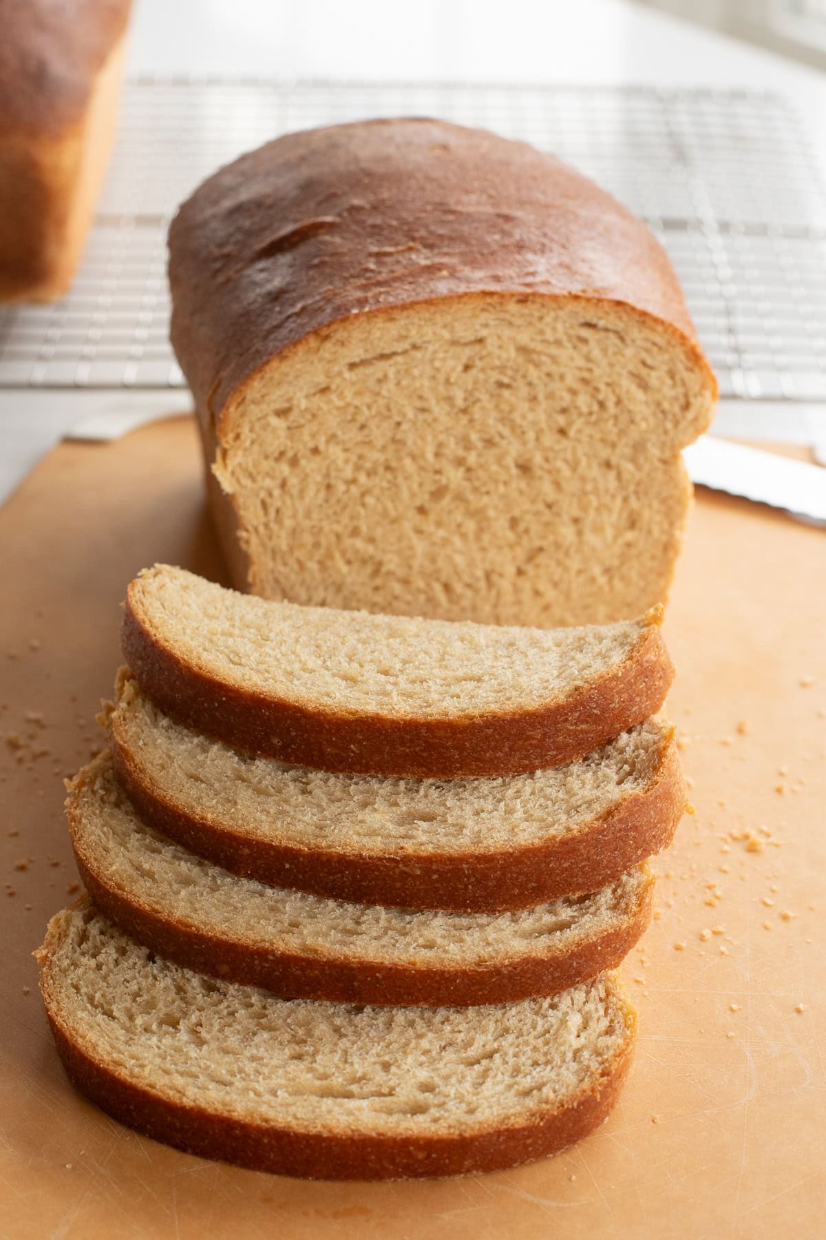 Fresh milled flour bread on cutting board with half a loaf and slices in front.