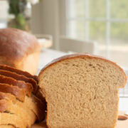 fresh milled flour bread on a cutting board, half and slices.