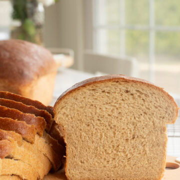 fresh milled flour bread on a cutting board, half and slices.
