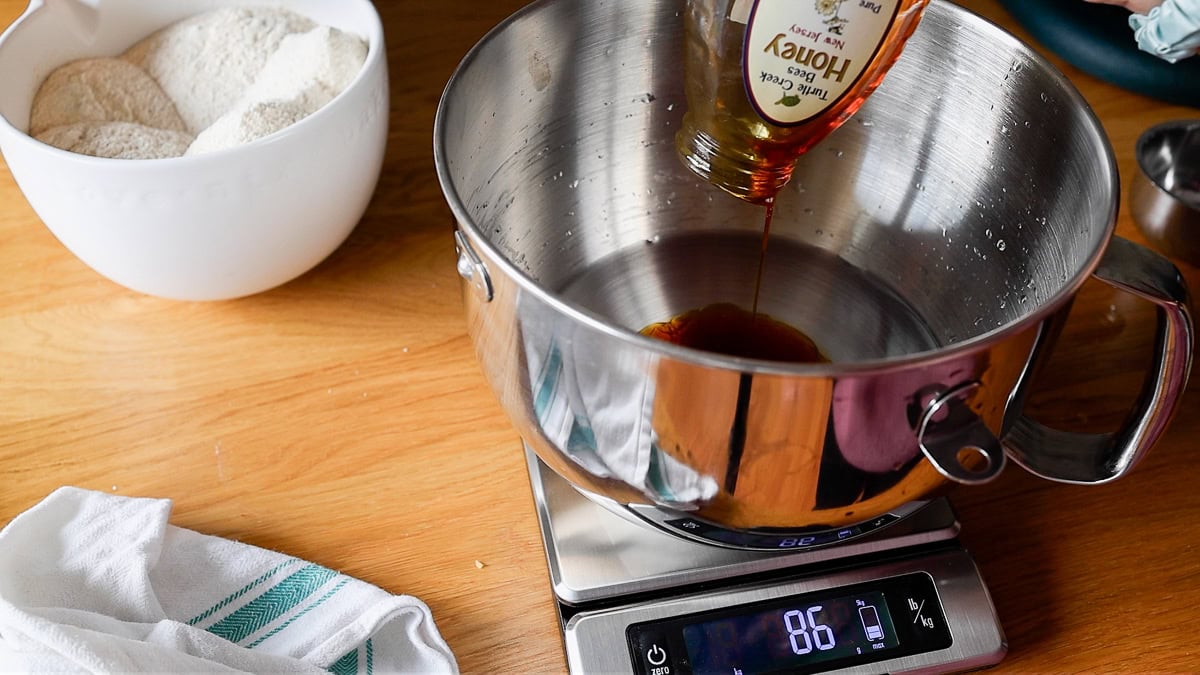 adding liquids like honey to a stand mixer bowl.