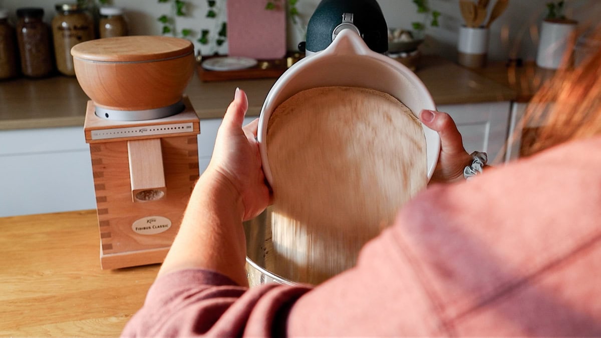 adding fresh milled flour to mixer bowl with liquids.
