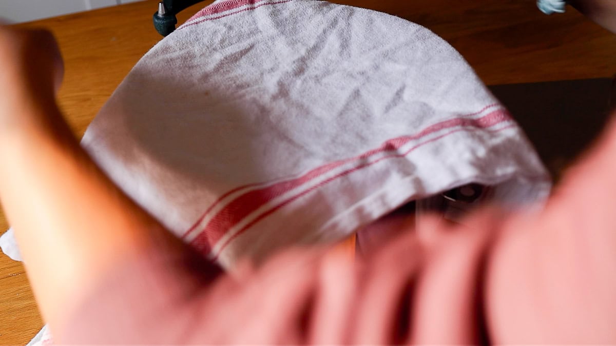 Covering dough with damp kitchen cloth.