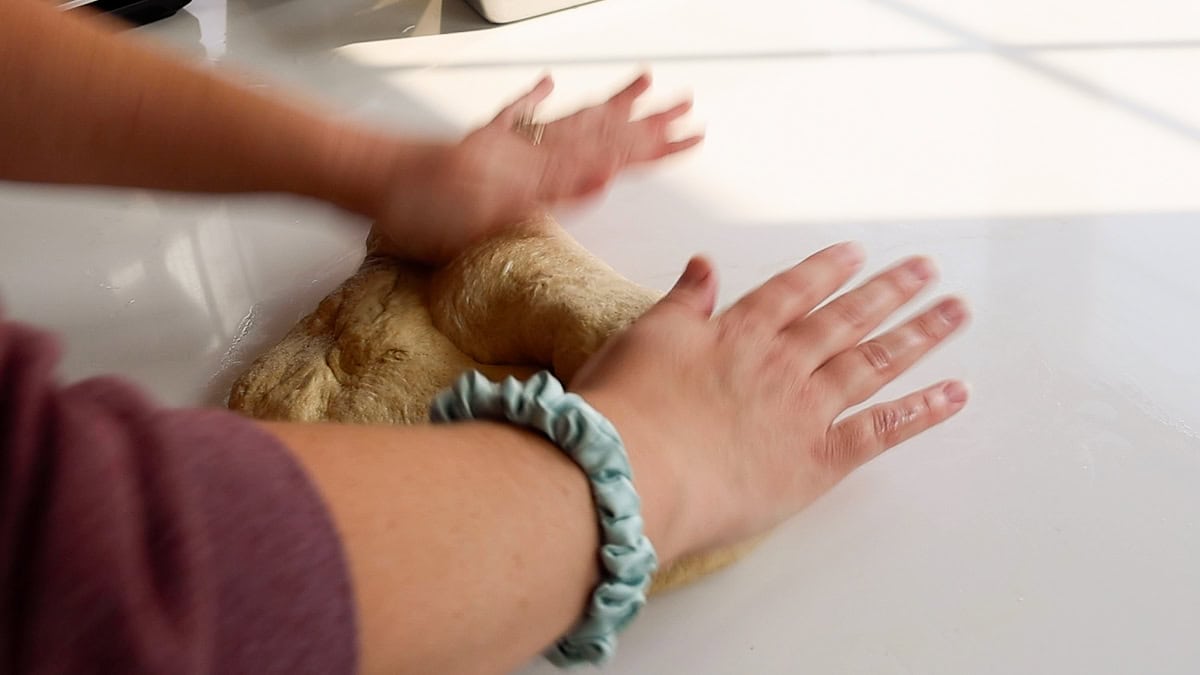 hands shaping fresh milled flour bread recipe into loaves.