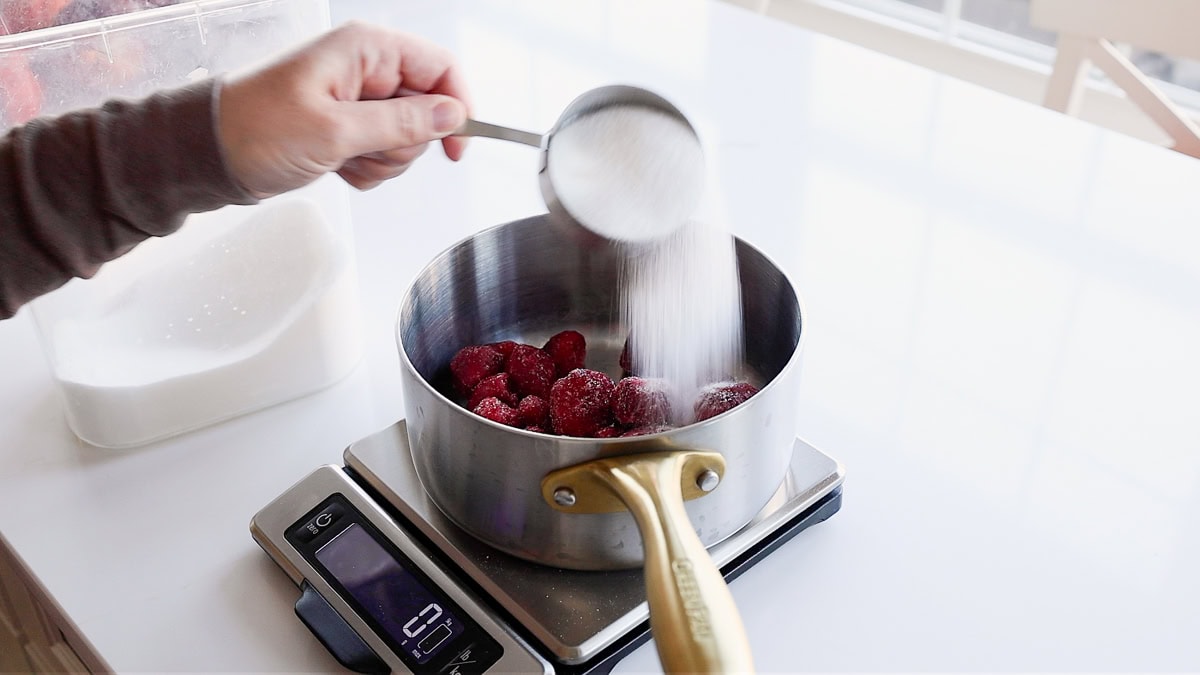 strawberries and sugar in sauce pan on scale.