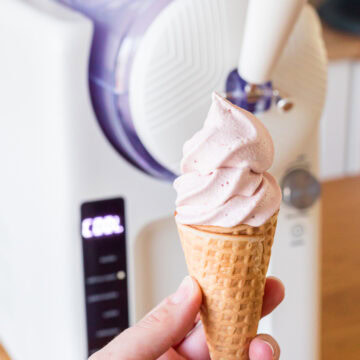 hand holding strawberry soft serve with greenpan frost in the background.