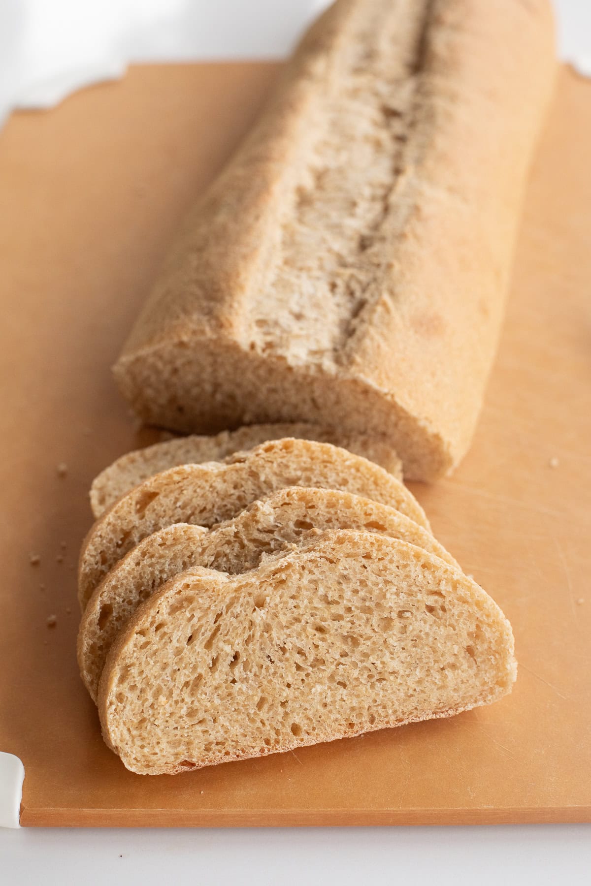 Fresh milled flour on a cutting board half not sliced and four slices in front.