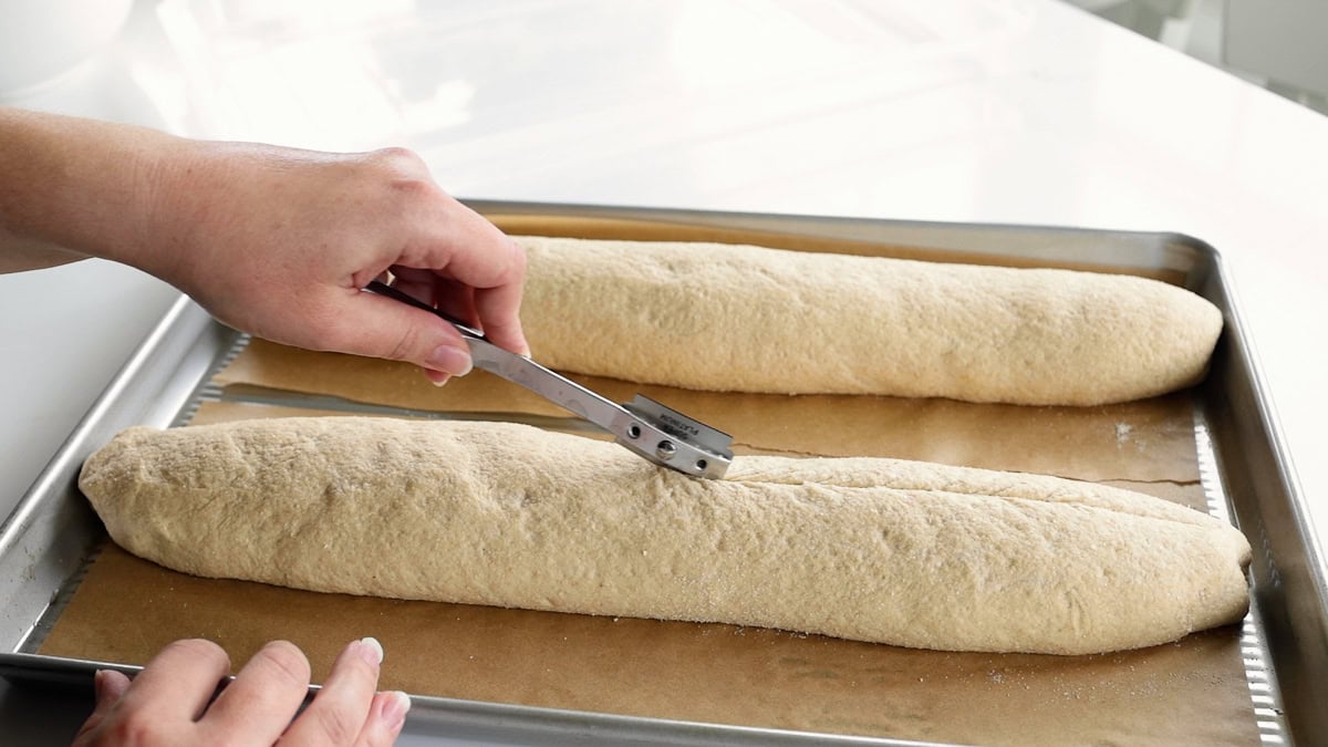 scoring fresh milled french bread with bread lame.