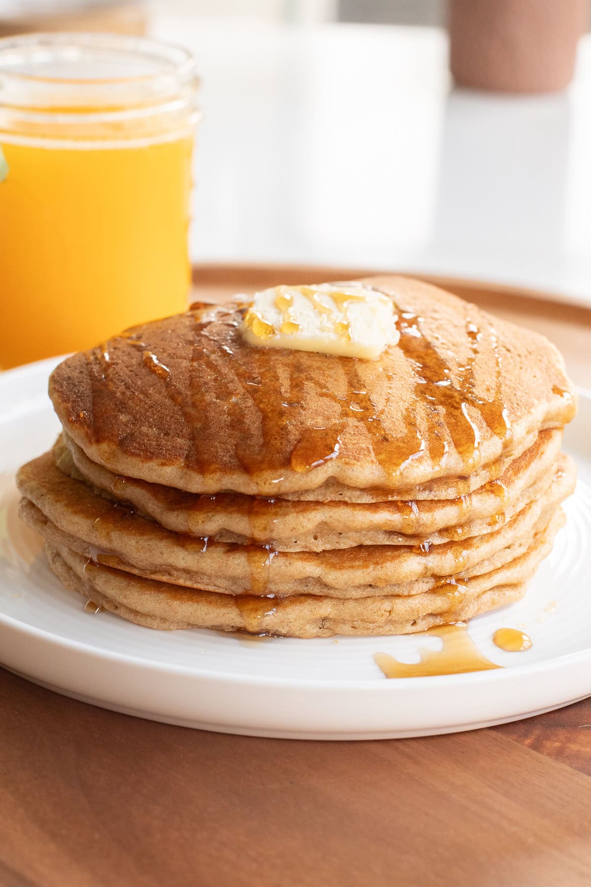 Stack of Einkorn pancakes with a pat of butter and a drizzle of maple syrup.