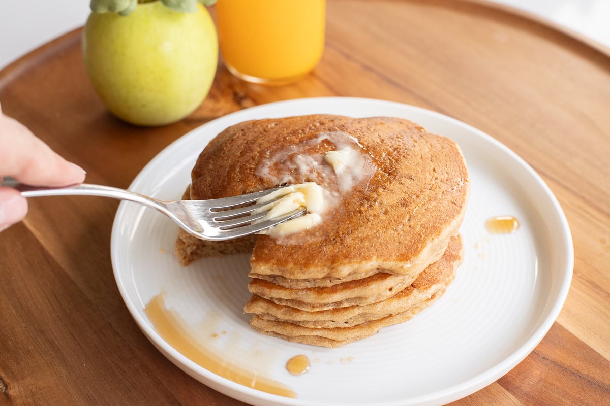 fork spreading softened warm butter on pancakes.